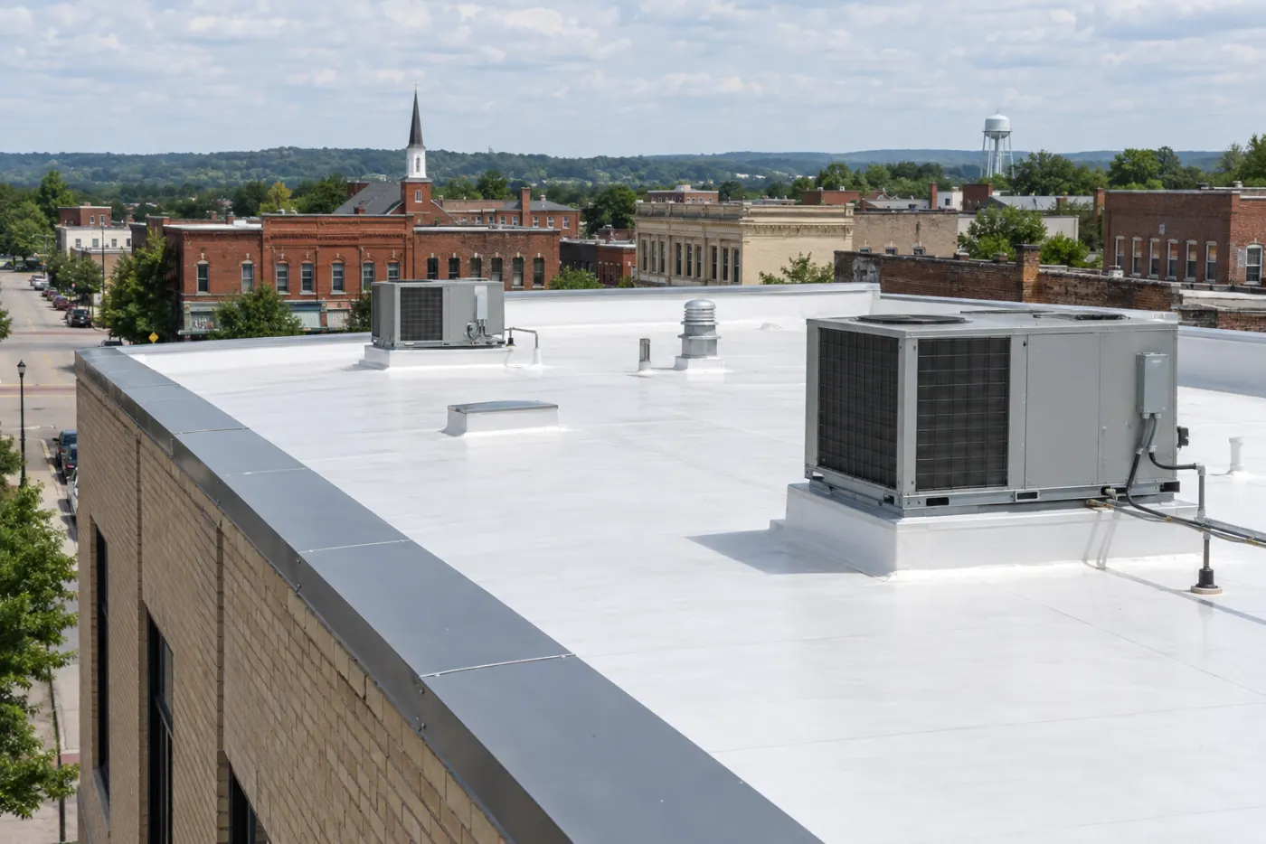 White single-ply membrane flat roof with rooftop HVAC units on a brick commercial building in a small Ohio downtown