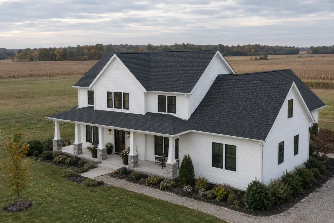 Two-story white farmhouse with a charcoal architectural shingle roof beside open Ohio farmland under an overcast sky