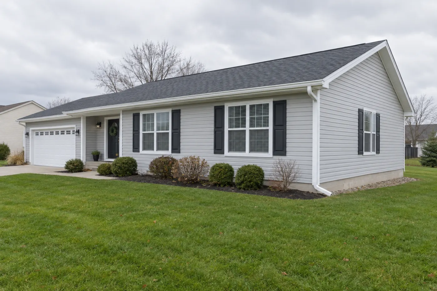 Single-story home with light gray vinyl siding, white trim, and new white seamless gutters